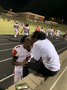 two people kissing each other on a football field