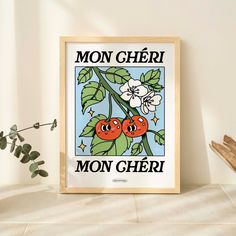 a framed poster with two cherries on a branch in front of a white wall