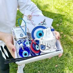 a person holding a box filled with assorted items on the grass in their hands