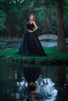 a woman in a black dress is standing by the water