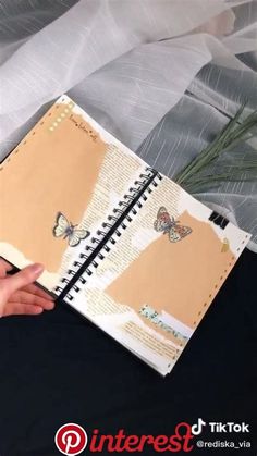 a person holding an open notebook with butterflies on it and writing down the pages in front of them