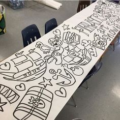 a long table covered in black and white doodles with chairs next to it