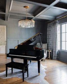 a living room with a grand piano and chandelier hanging from it's ceiling