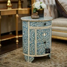 Photo copyright © Grandeur Crafts. All rights reserved. Do not use without permission. This exquisite round end table showcases a beautiful floral pattern in light Blue bone inlay, meticulously handcrafted for a unique touch. The sturdy black wooden legs complement the design, blending classic style with natural elegance. With a convenient single drawer and door, it offers both storage and sophistication, making it ideal as a bedside table, accent piece, or sofa companion. Each piece is one-of-a Round End Table, Round Light, Blue Floral Pattern, Wooden Leg, Space Organizer, Bone Inlay, End Table, Bedside Table, Accent Pieces