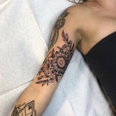 a woman laying in bed with a tattoo on her arm