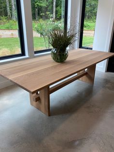 a wooden table sitting in front of two large windows