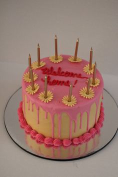 a pink and yellow birthday cake with candles