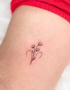 a small flower tattoo on the back of a woman's thigh, which is sitting on top of a bed