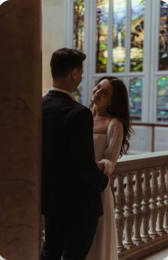 a man and woman standing next to each other in front of a stained glass window