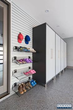 there are many pairs of shoes on the shelves in this room with white walls and gray flooring