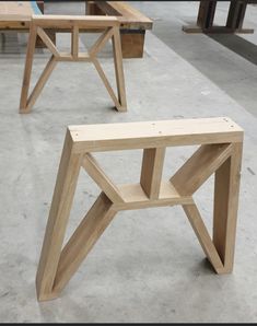 two wooden benches sitting next to each other on cement floored area with tables and benches in the background