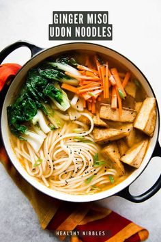 a bowl filled with noodles, carrots and greens