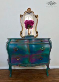 a blue and green dresser with flowers on top