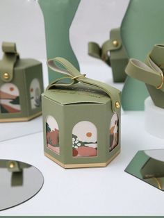 some green boxes with designs on them sitting on a white table and one has a bow at the top