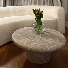 a vase with flowers sitting on top of a table in front of a white couch