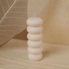 a white candle sitting on top of a wooden table