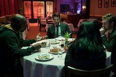 a group of people sitting at a table eating food and talking to each other in a restaurant