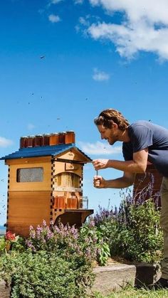 a man standing in front of a beehive and looking at the bees flying around