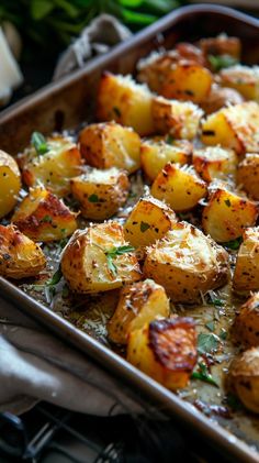 a pan filled with cooked potatoes covered in parmesan cheese and garnished with herbs