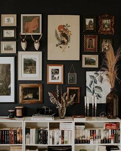 a bookshelf filled with lots of books next to a wall covered in pictures