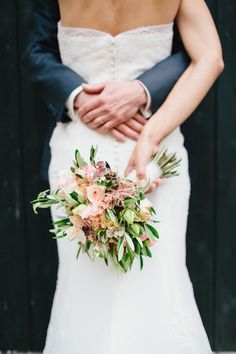 the bride and groom are holding each other's hands while they hold their bouquet