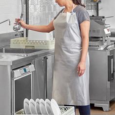 a woman in an apron is washing dishes