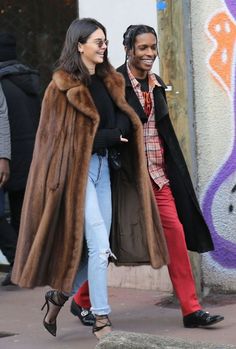 a man and woman are walking down the street with fur on their coats, one is wearing