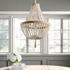 Unique prints for a travel look. Made of metal and wood beads, this chandelier has an antique metal finish. Its circular frame supports Four E12 base bulbs and a shade composed of cascading natural pale yellow wood beads Aiwen 4-Light White Farmhouse Beaded Chandelier | P-PZE-2508E Boho Chandelier Dining Room, Coastal Chandelier Dining Room, Beaded Chandelier Dining Room, Modern Coastal Lighting, Beachy Chandelier, White Beaded Chandelier, White Bead Chandelier, Lana Wood, Beaded Light Fixture