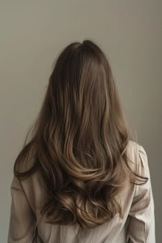 Woman with long, wavy brown hair facing away from the camera against a neutral background. Old Money Straight Hair, Old Money Brunette Short Hair, Old Money Brunette Hair Short, Old Money Curly Hair, Men Undercut, Rambut Brunette, Hairstyle Men, Honey Brown Hair