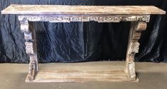 an old wooden table with carvings on the top and bottom, against a black background