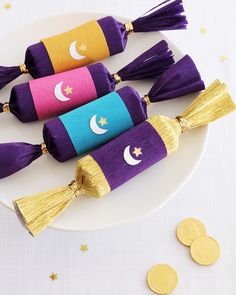 three purple and gold tassels on a white plate next to some golden coins