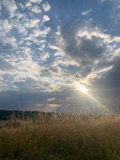 the sun shines brightly through clouds over an open field