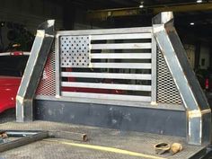 an american flag is on the back of a pickup truck in a garage with other vehicles