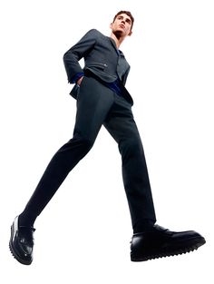 a man in a suit and tie is walking with his hands on his hips while wearing black shoes