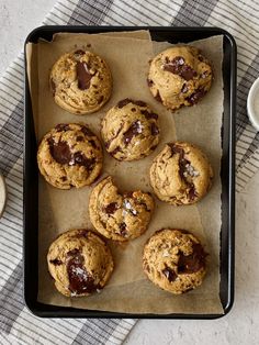 chocolate chip cookies on a baking sheet next to a cup of coffee and a napkin