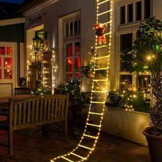 a ladder lit up with christmas lights in front of a house