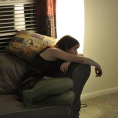 a woman sitting on top of a couch next to a window