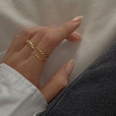 a woman's hand with a gold ring on her finger and a white shirt