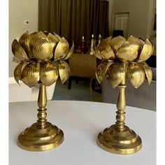 two golden candlesticks sitting on top of a white table