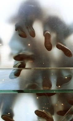 there are many pairs of shoes in the reflection of a glass shelf with silverware on it