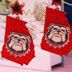 the earrings are decorated with red glitters and a bulldog head on it's ear