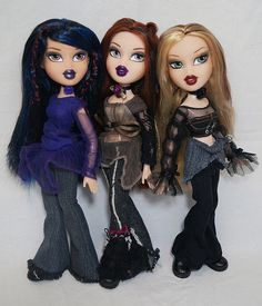 three dolls are standing next to each other on a white background, one is wearing black and the other has blue eyes