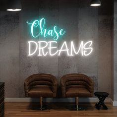 two brown chairs sitting in front of a neon sign that says chase dreams on the wall