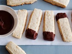 chocolate dipped shortbreads are lined up on a paper towel next to a bowl of dipping sauce