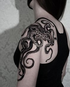 an octopus tattoo on the back of a woman's shoulder and arm is shown