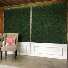 a chair sitting in front of a wall covered with green grass and two white doors