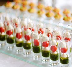 many small cups filled with food on top of a glass table covered in sauces and condiments