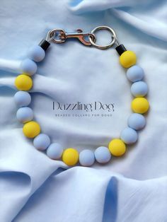 a yellow and blue beaded bracelet on a white sheet with the words dazzling dog written below it