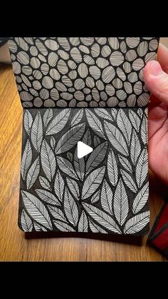 someone is holding up a card case that has an image of leaves and triangles on it