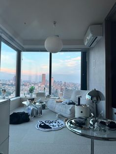 a living room filled with furniture and large windows overlooking a cityscape in the distance